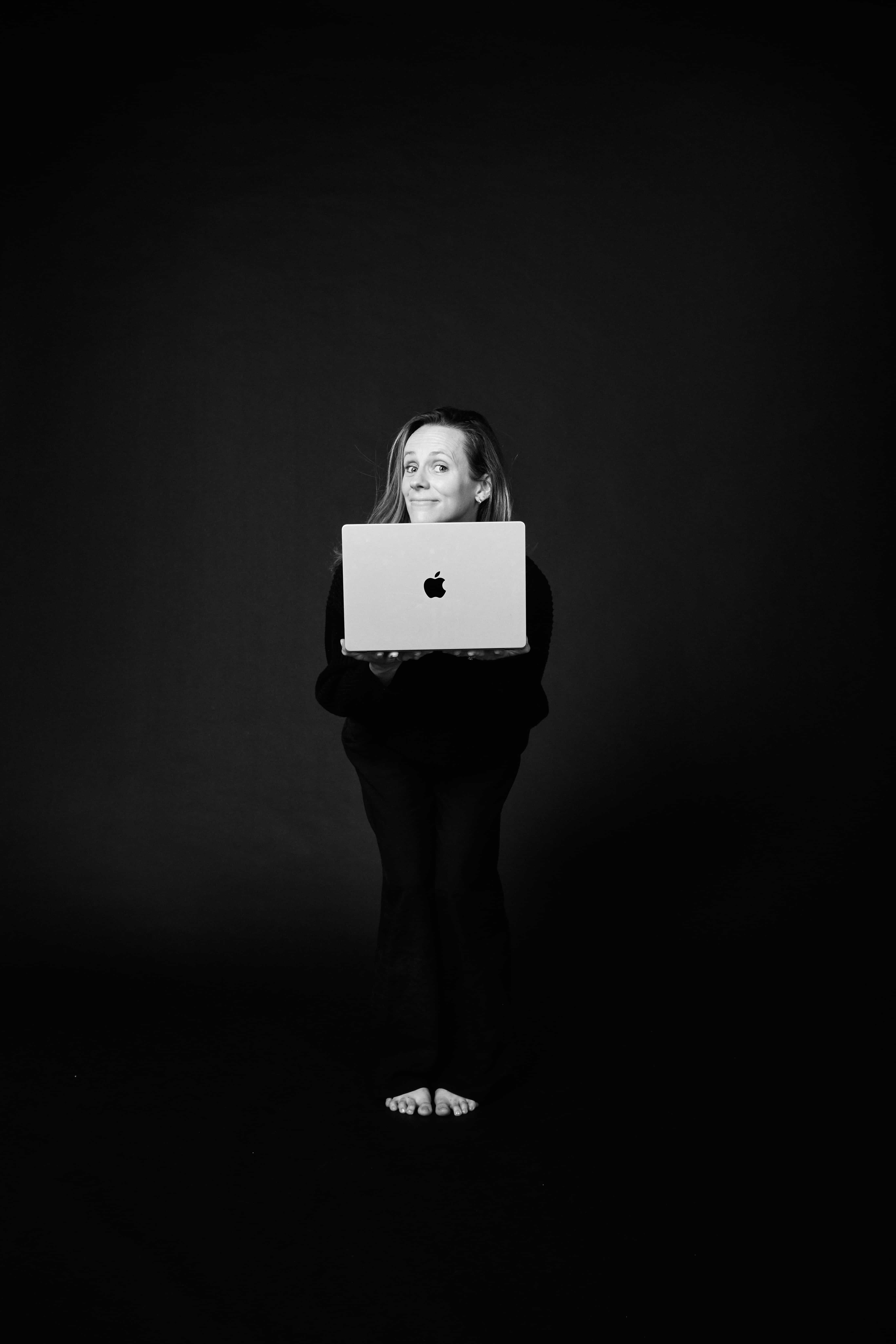 Chloe holding up an open laptop, smiling